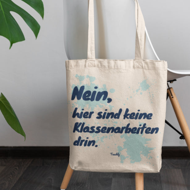 Die Teachly Bio-Baumwoll Tasche mit lustigem Nein, hier sind keine Klassenarbeiten drin Motiv und Mint Design für Lehrerinnen und Lehrer um einen Stuhl gehangen