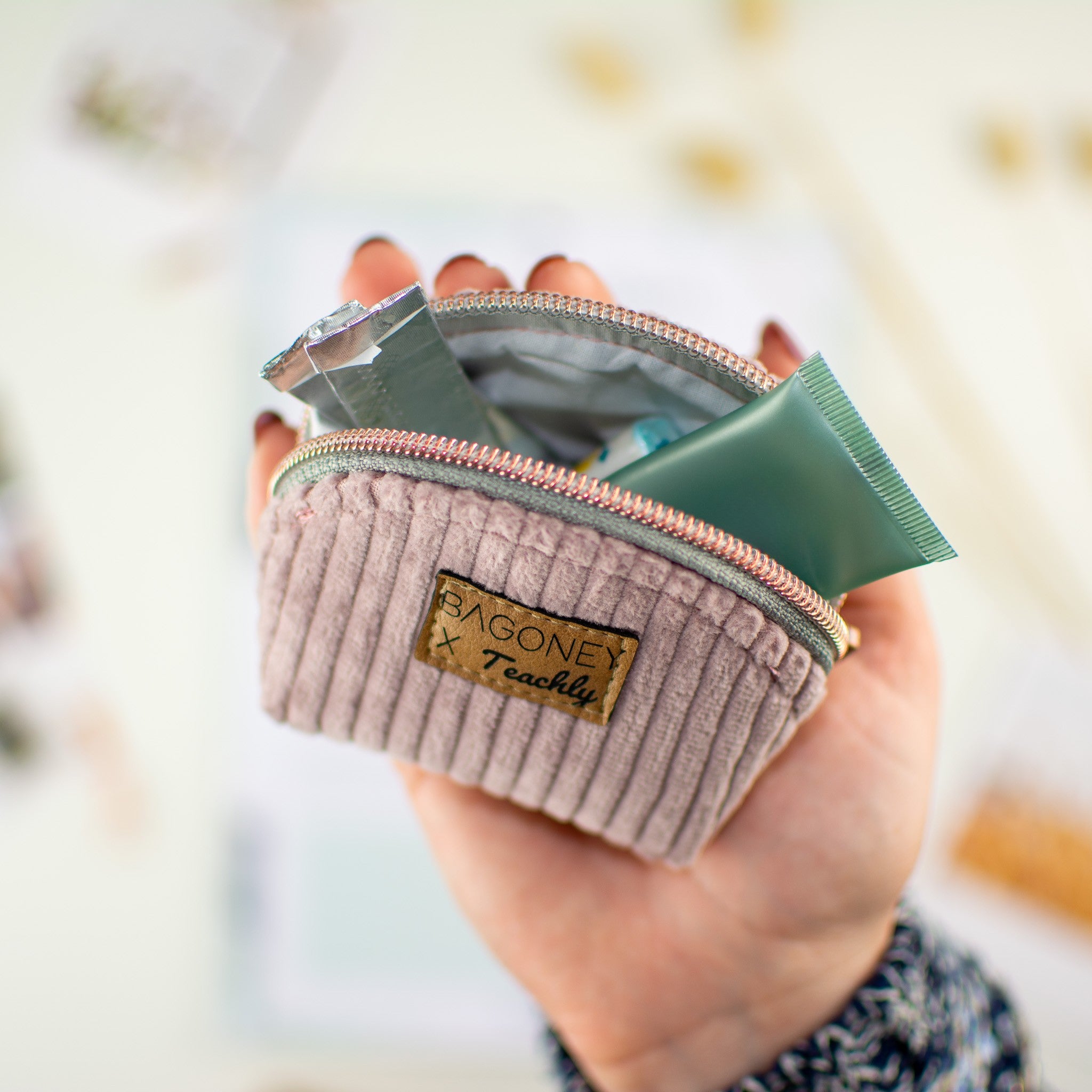 Das Teachly x Bagoney Mäppchen Casey S in einer Hand, befüllt mit kleinen Produkten für den alltäglichen Bedarf.