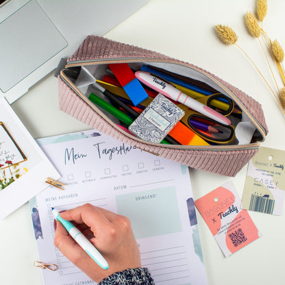 Das in Kooperation von Bagoney und Teachly entstandene CASEY L Cordstoff Mäppchen bzw. Federtasche gefüllt mit Stiften, Patronen, Radiergummis und Schere neben Schreibwaren