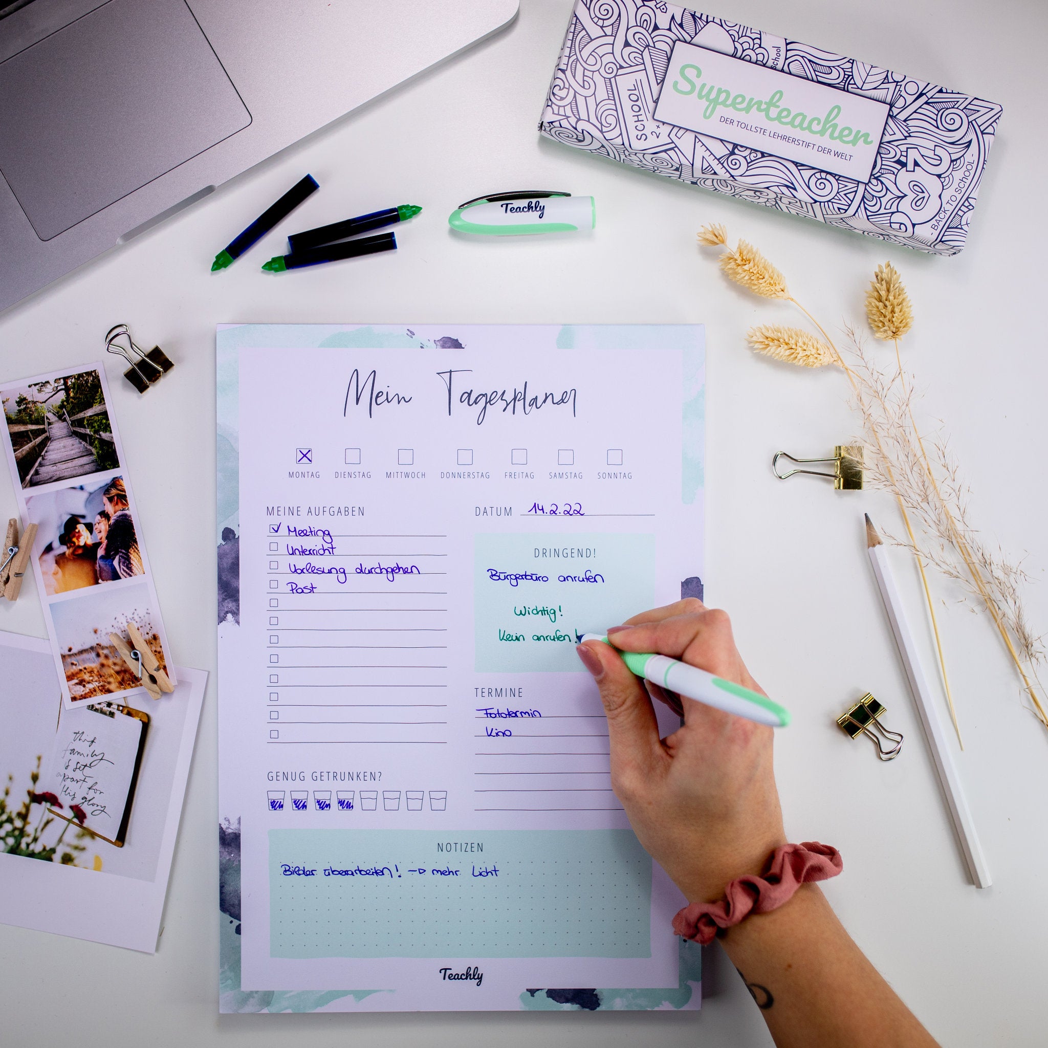 Eine Person schreibt auf dem Teachly Tagesplaner mit Abschnitten für Notizen, Dringendes, Termine sowie Aktivitäten, mit einem schönen pastellfarbenen Aquarelldesign.